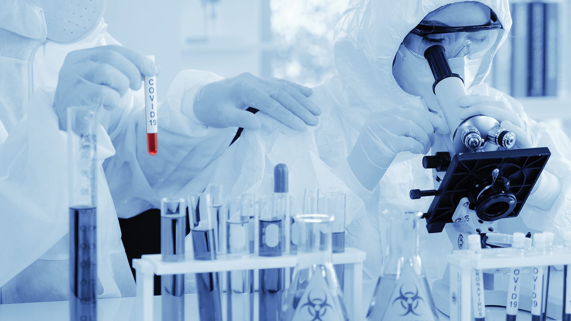 Researchers in protective gear examine samples under the microscope 