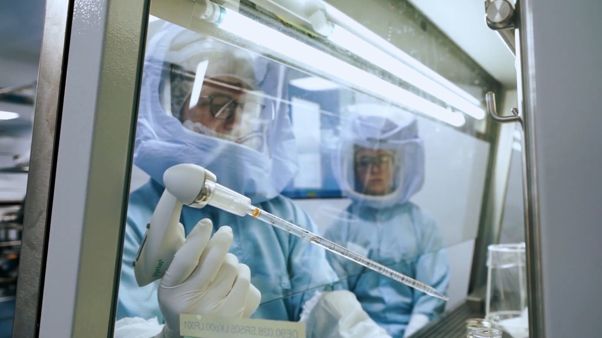 A researcher in protective gear operates complex apparatus in the lab