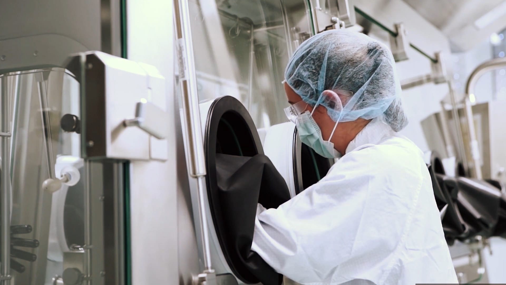 Ein Labormitarbeiter in Schutzkleidung arbeitet an einem Abschnitt der Produktionsstrecke für den mRNA-Impfstoff