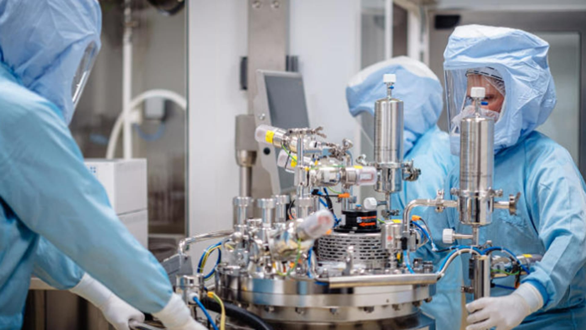 Labormitarbeiter in Schutzkleidung preparieren einen Abschnitt der Produktionsstrecke für den mRNA-Impfstoff
