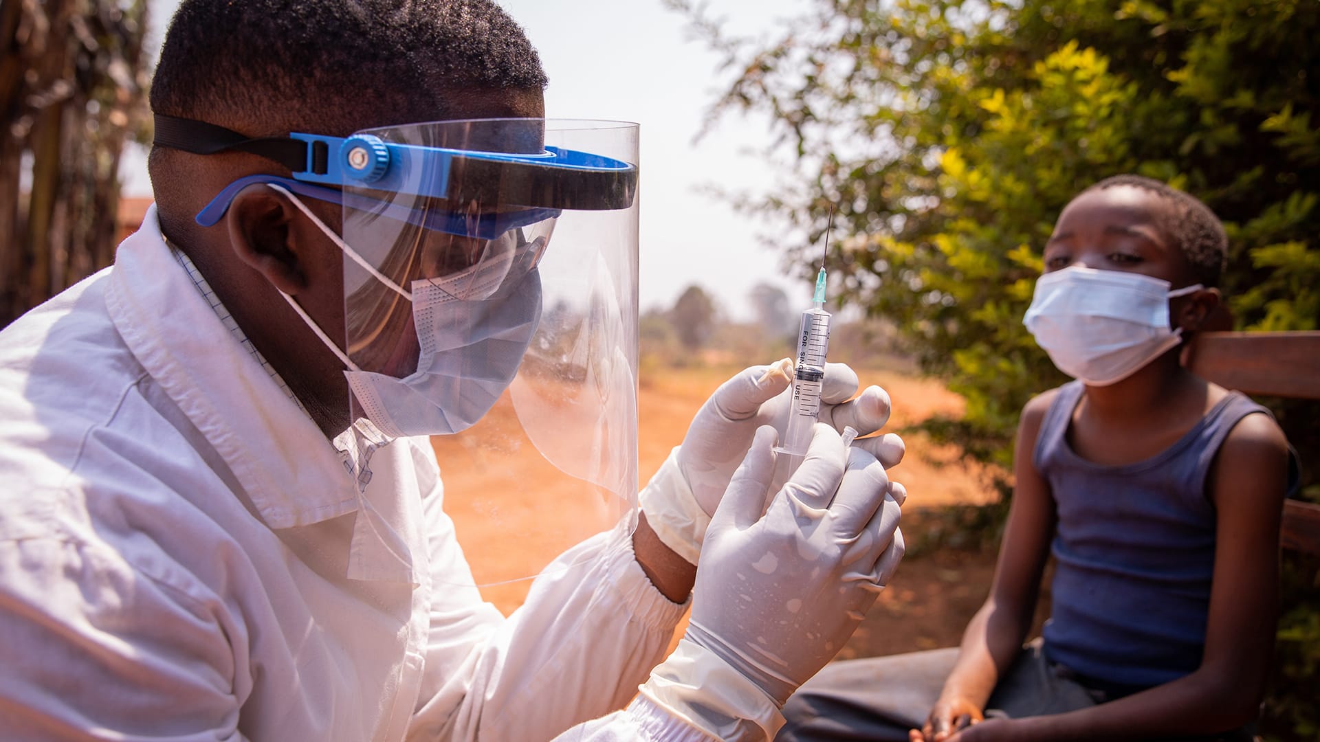 An African doctor vaccinates a boy against COVID-19