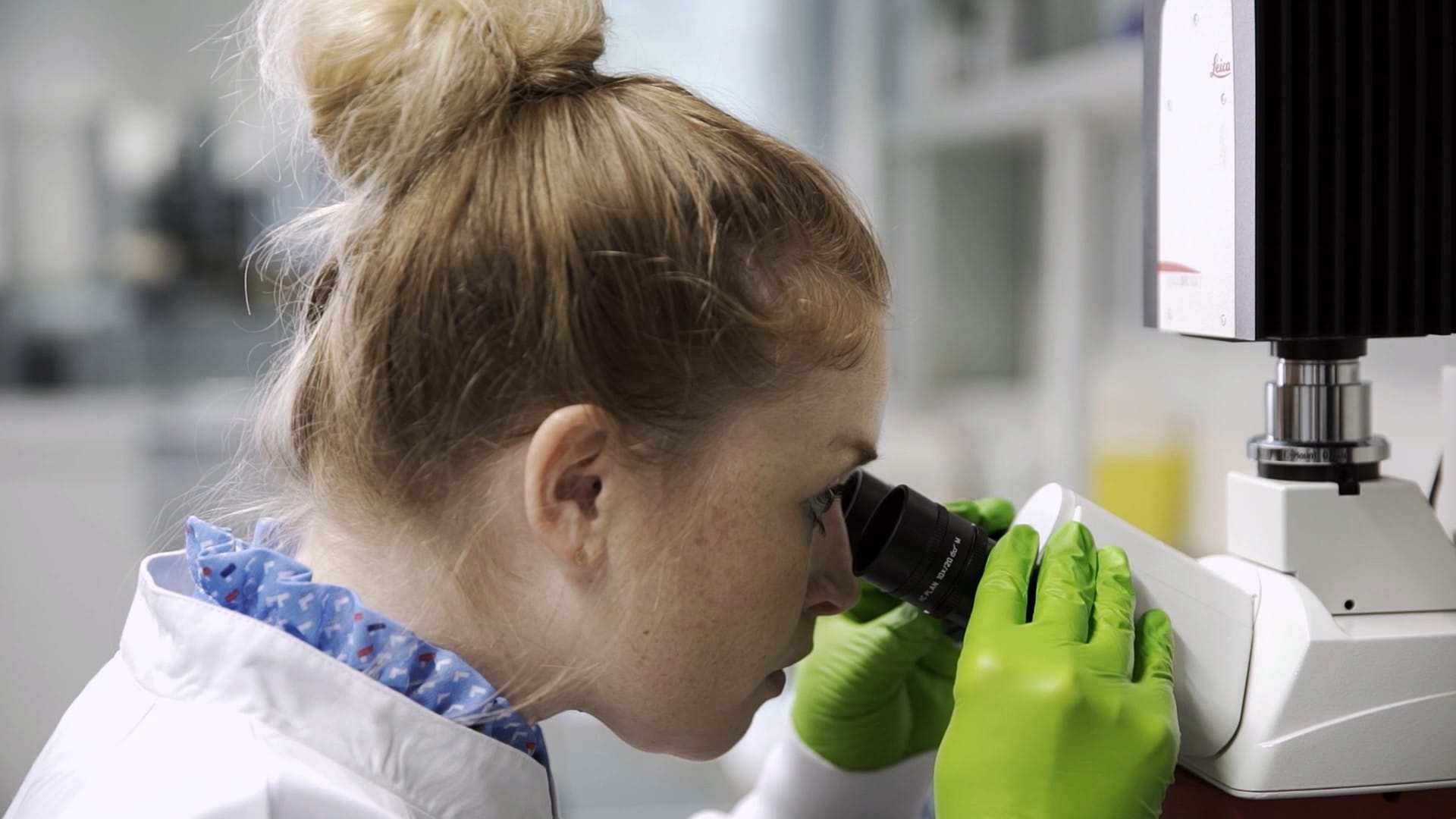 Eine junge Frau untersucht Biomaterial unter dem Mikroskop